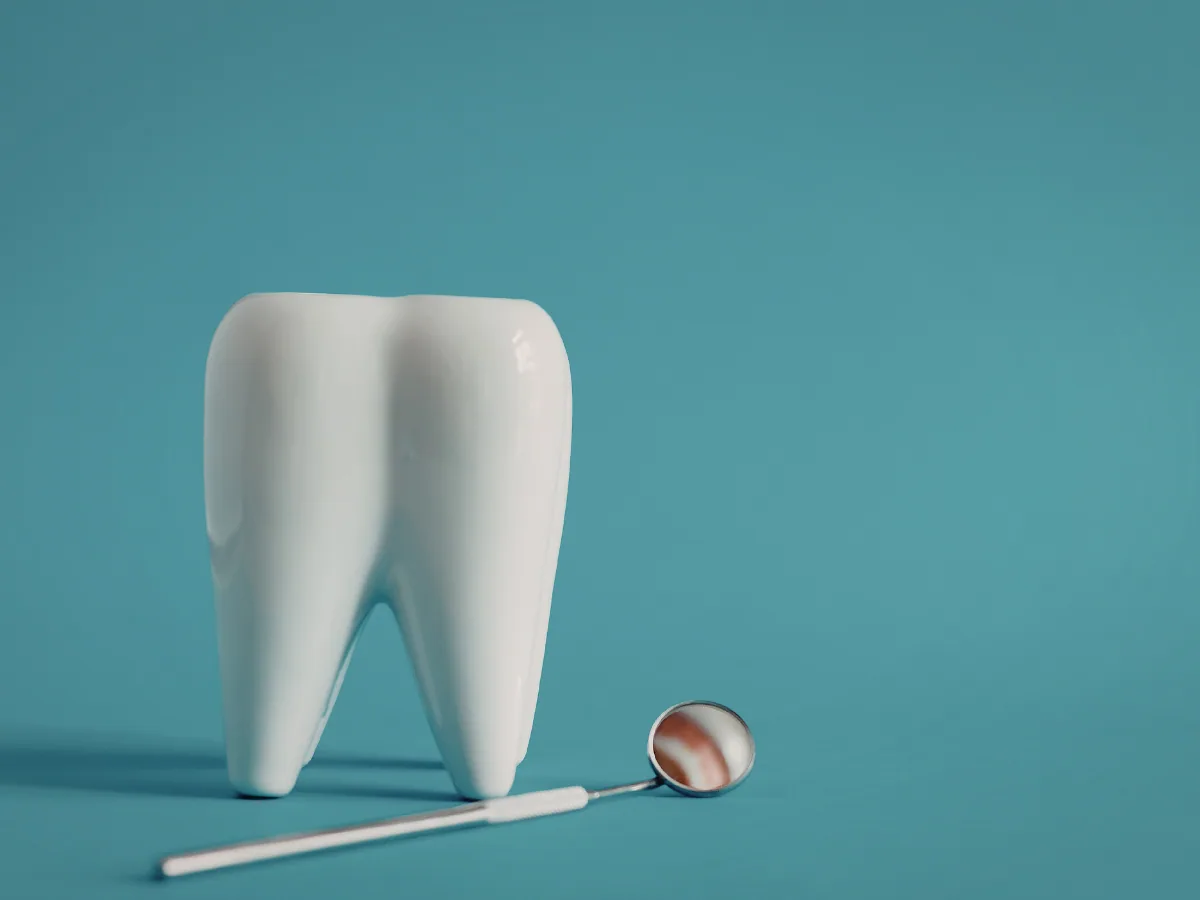 Emergency Dentist on Avenue Road | Broken Tooth Repair at North Toronto Dental Centre White ceramic tooth model and dental mirror on a teal background representing emergency broken tooth repair