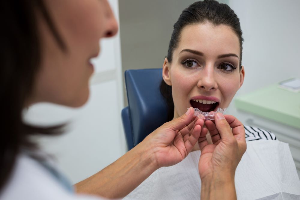 Dentist fitting clear aligner during Invisalign follow-up visit to monitor treatment timeline in North York